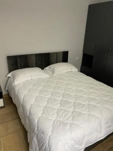 a large white bed with a wooden headboard in a bedroom at Eagle’s Nest in Shkodër