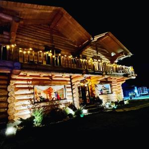 a log house with lights on it at night at The Mountain's Sea Chalet in Colibiţa