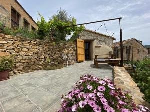 un patio con flores y una pared de piedra en Caseta de Magí en Ager