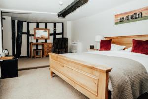 een slaapkamer met een groot bed met rode kussens bij The Peppermill Town house Hotel & Restaurant in Devizes