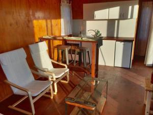une cuisine avec des chaises blanches et une table en verre dans l'établissement Bungalow de campo Nabucco - sierras, naturaleza y descanso, à Minas
