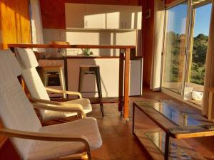 a living room with chairs and a table and a counter at Bungalow de campo Nabucco - sierras, naturaleza y descanso in Minas
