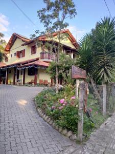 un cartel delante de una casa con flores en Pousada Unser Haus en São Francisco de Paula