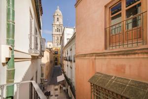 an alley between two buildings with a clock tower at Solaga - Larios Suites in M&aacute;laga