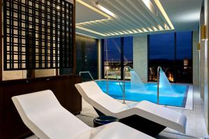 a room with white chairs and a swimming pool at The Parkgate Hotel in Cardiff