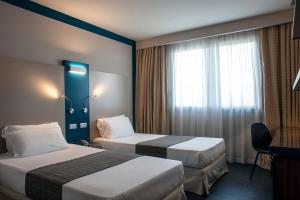 A bed or beds in a room at La Meridiana Bleisure Hotel