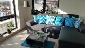 una sala de estar con un sofá gris con almohadas azules y blancas en Azzurro-Top floor apartment in quiet neighborhood, Free private parking en Varna