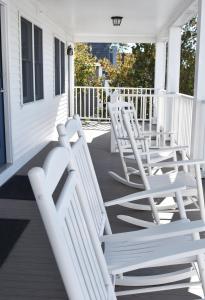 a group of white chairs sitting on a porch at The Whaler's Inn in Mystic