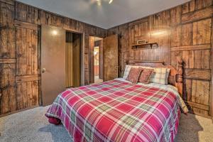 1 dormitorio con paredes de madera y 1 cama. en Roscommon Cabin Less Than 3 Mi to Higgins Lake, en Roscommon