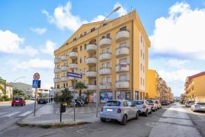 Un edificio amarillo con coches aparcados delante. en Adriatico apartment, en Alghero