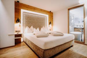 a bedroom with a large bed and a bathroom at Alpinhotel Berghaus spa in Tux