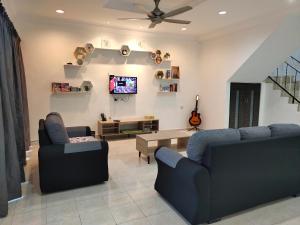 a living room with two blue couches and a tv at U&I HOMESTAY KAMPAR in Kampar