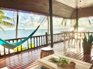 a porch with a hammock and a view of the ocean at Hin Kong Sunset Beach Front House in Srithanu