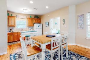 uma cozinha com uma mesa de madeira e cadeiras brancas em Down the Shore em Gulf Shores