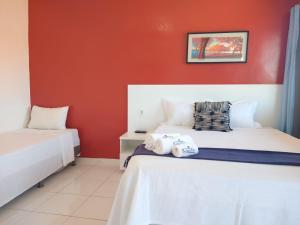 een slaapkamer met 2 bedden en een rode muur bij Pousada Beira Rio Parnaíba in Parnaíba