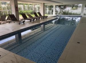 a large swimming pool with lounge chairs and a swimming pool at Flat 5 estrelas charmoso na Granja Viana in Cotia