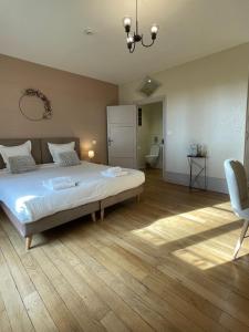 una camera con un grande letto e una sedia di La Maison Verneuil a Paray-le-Monial