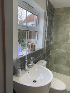 łazienka z umywalką, toaletą i oknem w obiekcie Arden House NEC Birmingham w mieście Bickenhill