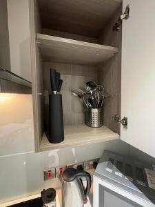 a cupboard with utensils in it next to a microwave at Quay Apartments Manchester in Manchester