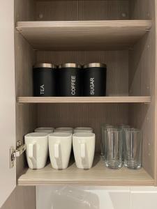 a shelf with a bunch of cups and glasses on it at Quay Apartments Manchester in Manchester