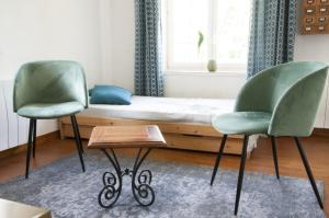 two green chairs and a bed in a room at La Maison des Tilleuls in Saint-Germain-sur-Sèves