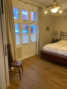 a bedroom with a bed and a chair and windows at Apartments im Kaffeehaus Heldt in Eckernförde