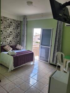 1 dormitorio con 1 cama y balcón con TV en Hotel Duarte, en Palmitinho