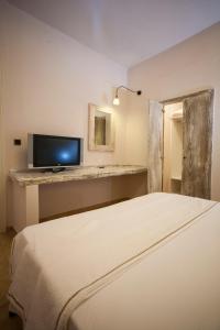 um quarto com uma cama branca e uma televisão em Ammos Naxos Exclusive Apartments & Studios em Naxos Chora