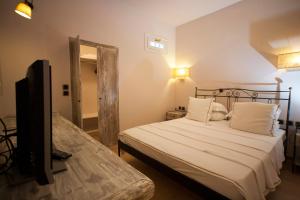 a bedroom with a bed and a flat screen tv at Ammos Naxos Exclusive Apartments & Studios in Naxos Chora