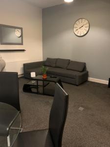 a living room with a couch and a clock on the wall at Town Centre Kilmarnock in Kilmarnock