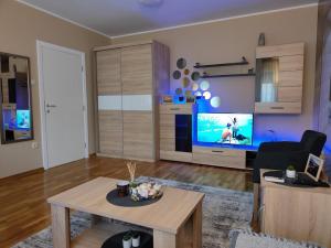 a living room with a table and a large screen tv at Apartman ESPRESSO in Sremska Mitrovica