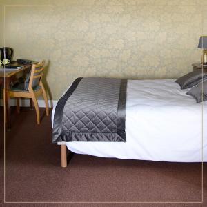 a bedroom with a bed and a desk and a table with a chair at Hôtel La Batisse in Crémieu