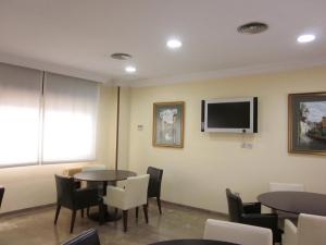 a waiting room with tables and chairs and a flat screen tv at Hotel Elena María in Granada
