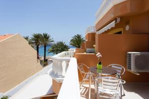 einen Balkon mit einem Tisch, Stühlen und Meerblick in der Unterkunft Tenerife Royal Gardens - Las Vistas TRG - Viviendas Vacacionales in Playa de las Americas