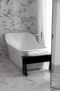 a white bath tub sitting in a bathroom next to a mirror at Yndo Hôtel in Bordeaux