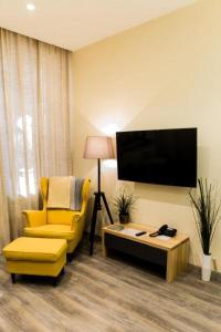 sala de estar con silla amarilla y TV en Malon apartments en Odesa