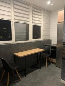 cocina con mesa, sillas y ventanas en Квартира в новобудові в районі автовокзал , поруч ТРЦ Арена, en Rivne