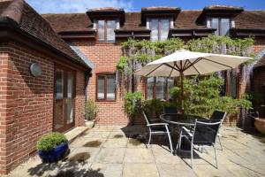 a patio with a table and an umbrella at Wisteria Way, Tangmere in Tangmere