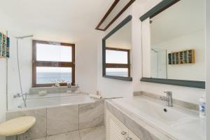 ein Badezimmer mit einer Badewanne, einem Waschbecken und einem Spiegel in der Unterkunft Premium Sesimbra Apartment, Private Beach Access, Garage, View in Sesimbra