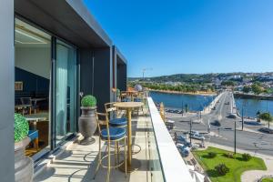 a balcony with a bar with a view of a river at Hästens Sleep Experience FLH Hotels Coimbra in Coimbra