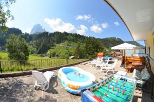 um pátio com uma banheira de hidromassagem, uma mesa e cadeiras em Garni Ossi em Santa Cristina in Val Gardena