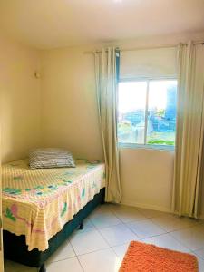 a small bedroom with a bed and a window at Apto lindo e aconchegante próximo a praia in Itapema