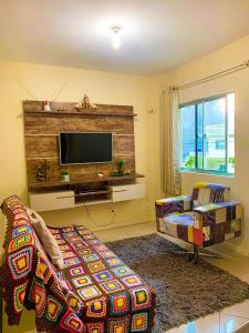uma sala de estar com um sofá e uma televisão de ecrã plano em Apto lindo e aconchegante próximo a praia em Itapema