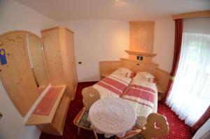 a small bedroom with a bed and a table at Garni Ossi in Santa Cristina Gherdëina