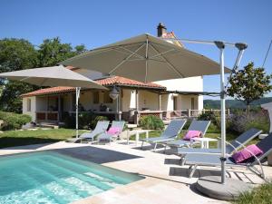 - un groupe de chaises et un parasol à côté de la piscine dans l'établissement Villa la Fontaine, à Viré