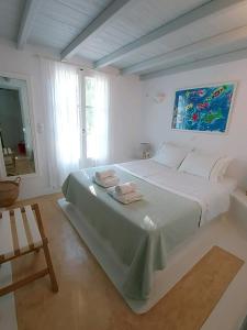 a white bedroom with a large bed with two towels on it at Simos suites in Elafonisos