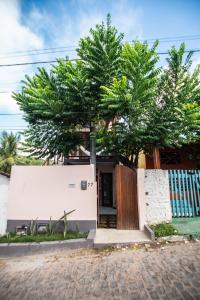 a house with a tree in front of a building at Estadia Poética in Pipa