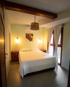 a bedroom with a white bed and a window at Estadia Poética in Pipa