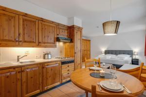 a kitchen with wooden cabinets and a table and a bed at Gemütliches Appartement nähe Skipiste in Deutschberg