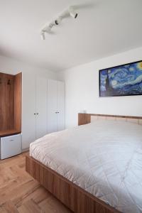 1 dormitorio con 1 cama grande y una pintura en la pared en HVT Comfort Apartments, en Mezőkövesd